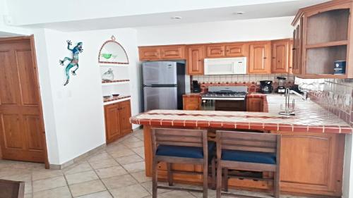 uma cozinha com armários de madeira e uma ilha com bancos de bar em Villa Relax 3 by Kivoya em Puerto Peñasco