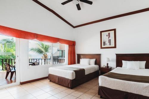 a bedroom with two beds and a large window at Hotel Cayman Suites in Monterrico