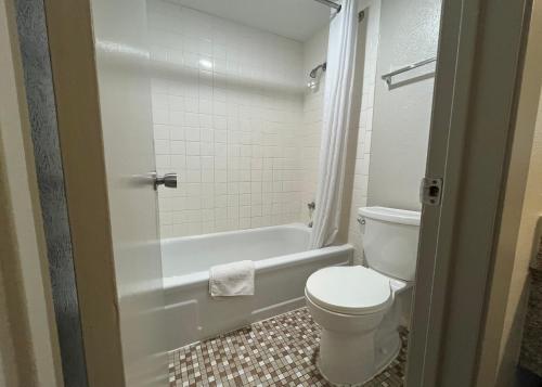 a bathroom with a toilet and a tub and a sink at EZ Travel Inn College Station in College Station