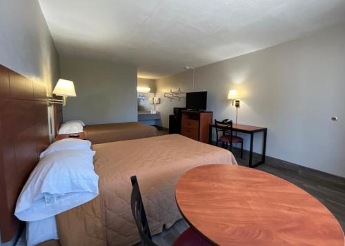 ein Hotelzimmer mit 2 Betten und einem Tisch in der Unterkunft EZ Travel Inn College Station in College Station