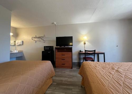 a hotel room with two beds and a desk and a television at EZ Travel Inn College Station in College Station