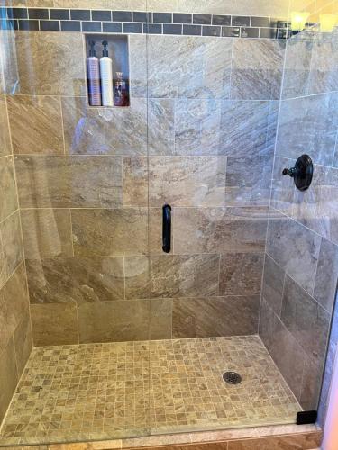ducha con puerta de cristal y suelo de baldosa en Celestial Casita, en Colorado Springs