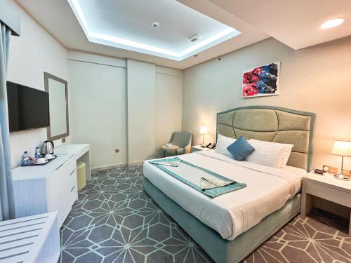 ein Hotelzimmer mit einem Bett und einem TV in der Unterkunft The Victory Hotel in Doha