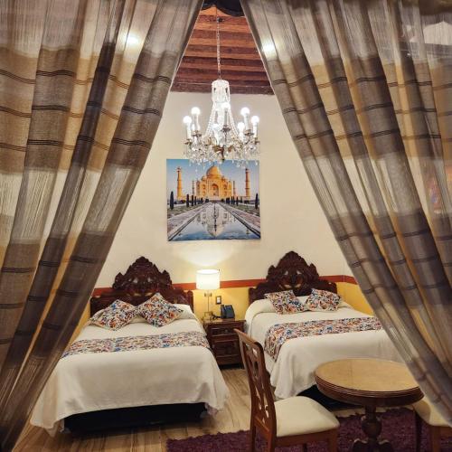 a bedroom with two beds and a chandelier at HOTEL CASA BAEZ in Pátzcuaro