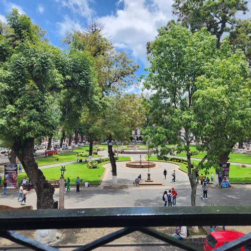 a park with people walking around a fountain and trees at HOTEL CASA BAEZ in Pátzcuaro