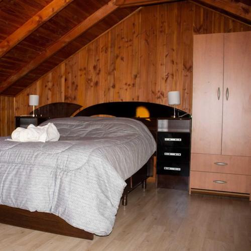 1 dormitorio con 1 cama y pared de madera en Cabañas Zu Hause, en Valdivia