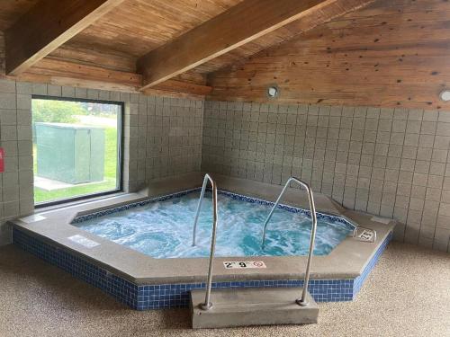 a large hot tub in a room with a window at AmericInn by Wyndham Ames in Ames