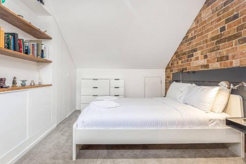 a bedroom with a white bed with a brick wall at A Charming Sunny Terrace in the Heart of Newtown in Sydney