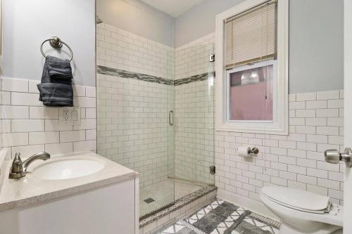 uma casa de banho com um chuveiro, um lavatório e um WC. em Live the Dream in Wrigleyville's 3BR Gem em Chicago