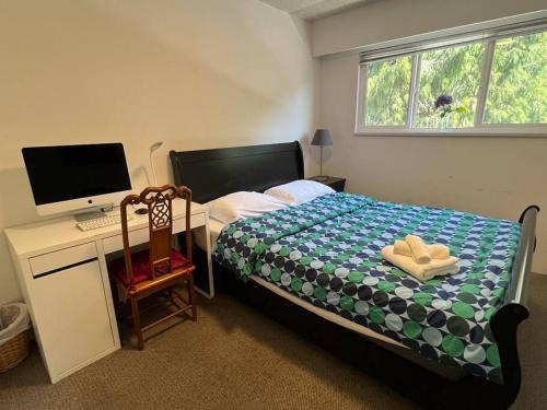 a bedroom with a bed and a desk with a computer at Two Bedrooms Marpole Vancouver in Vancouver