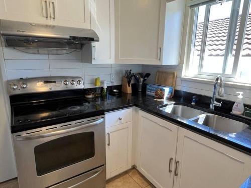 cocina con fregadero y fogones horno superior en Two Bedrooms Marpole Vancouver, en Vancouver