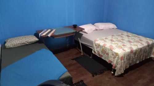 a small room with a bed and a table and blue walls at Big Hostel Brasil in Manaus