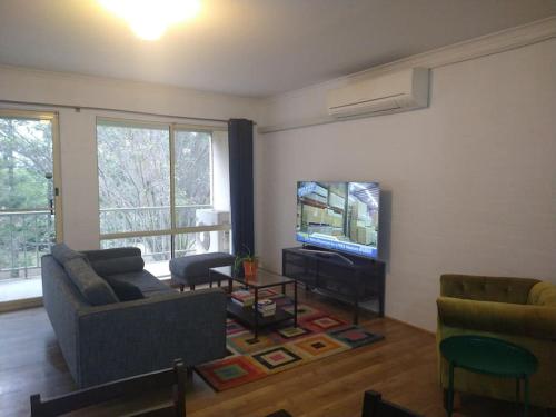 a living room with a couch and a flat screen tv at Beautiful Outlook, nr Canberra Hospital @Woden in Phillip