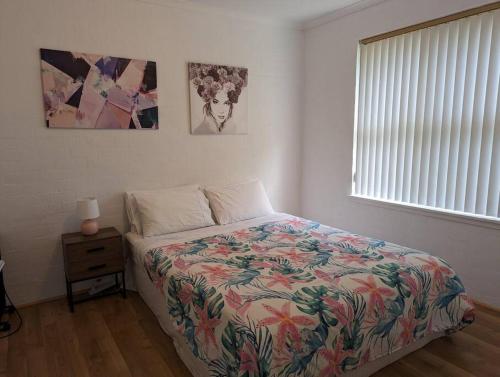 um quarto com uma cama com uma colcha colorida e uma janela em Beautiful Outlook, nr Canberra Hospital @Woden em Phillip