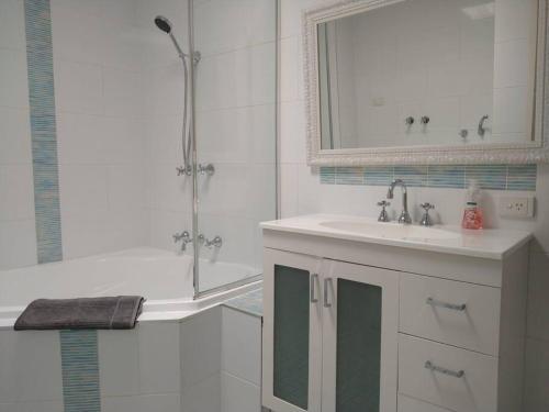 uma casa de banho branca com um lavatório e um chuveiro em Beautiful Outlook, nr Canberra Hospital @Woden em Phillip