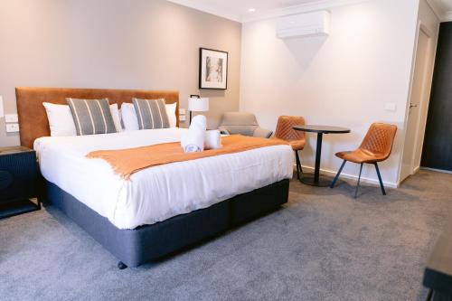 um quarto com uma cama grande com uma mesa e cadeiras em Wagga RSL Club Motel em Wagga Wagga