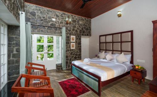 1 dormitorio con 1 cama grande y pared de piedra en 31st December Farms And Estates Munnar, en Munnar