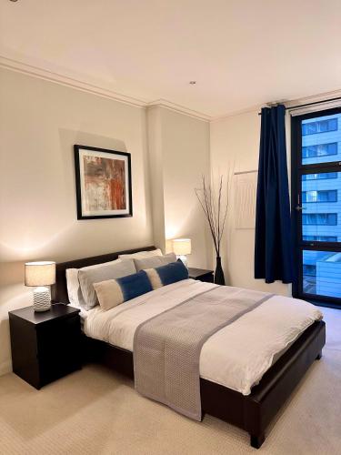 a bedroom with a large bed and a window at NEW Spacious One Bed Apartment Near Canary Wharf in London