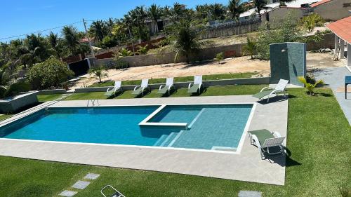 a swimming pool with a bunch of chairs around it at CHEZ TUPÃ SUÍTES in Uruau
