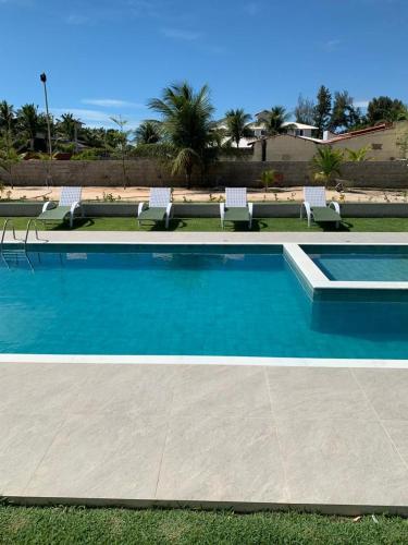 a swimming pool with chairs and blue water at CHEZ TUPÃ SUÍTES in Uruau