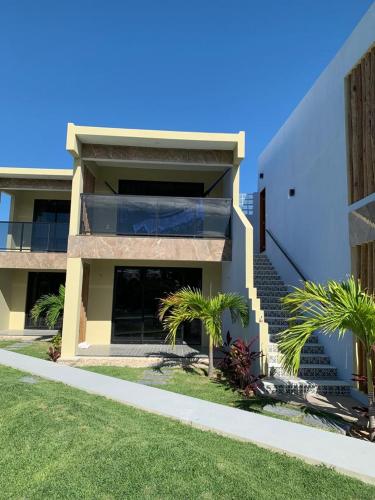 a building with palm trees in front of it at CHEZ TUPÃ SUÍTES in Uruau
