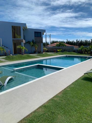 a swimming pool in front of a house at CHEZ TUPÃ SUÍTES in Uruau