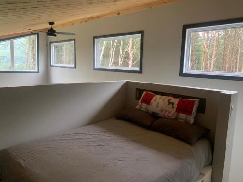 Ce lit se trouve dans une petite chambre avec 3 fenêtres. dans l'établissement Vallée bras du Nord Jumeau #1 avec spa, à Saint-Raymond