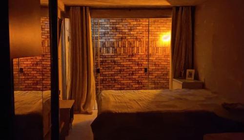 a bedroom with a bed and a brick wall at AP TROPICAL CENTER in Brasilia