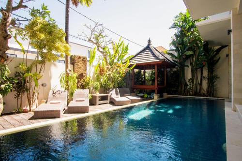 a swimming pool in a backyard with chairs and a house at Outpost Canggu in Canggu