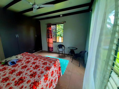 1 dormitorio con cama, mesa y ventana en Pacific Harbor Eco Villa and Shark Dive Accomodations, en Pacific Harbour