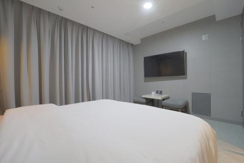 a bedroom with a white bed and a television at HOTEL YUNA Business in Busan