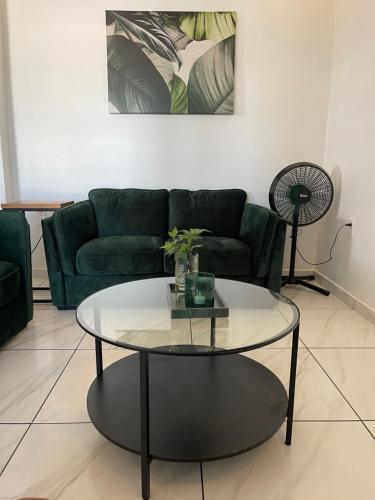a living room with a green couch and a glass table at Boa vista appartementen in Paramaribo