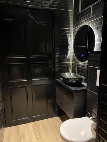 a black bathroom with a sink and a mirror at Boa vista appartementen in Paramaribo