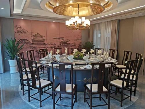Chongqing Jianfeng Hotel في Fuling: غرفة طعام مع طاولة وكراسي وثريا