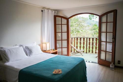 una camera da letto con un letto e una porta aperta di Guest House Fazenda do Francês & Culinária Francesa a Cachoeiras de Macacu