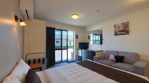 een slaapkamer met een bed, een bank en een televisie bij Airways Motel in Christchurch