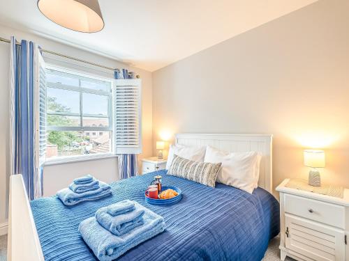 a bedroom with a blue bed with a bowl of fruit on it at Elwell Cottage in Beverley