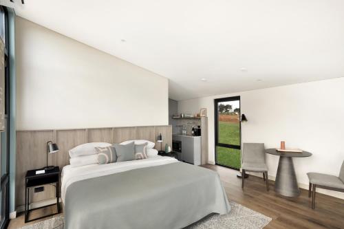 a bedroom with a large white bed and a table at The Lane Retreat in Pokolbin