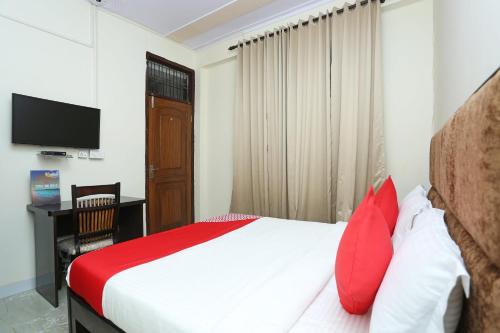 a bedroom with a bed with red pillows and a television at OYO Hotel Awesome Villa Near Appu Ghar in Gurgaon