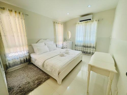 a white bedroom with a bed and a table at Chomdao house98 in Udon Thani