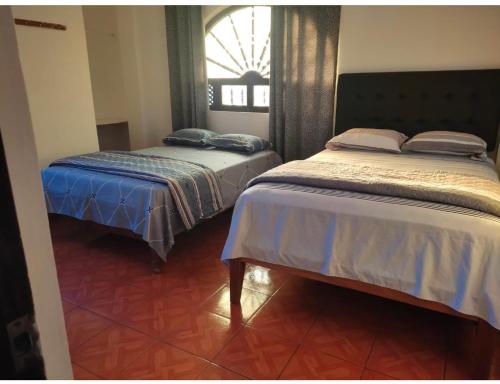 two twin beds in a room with a window at Hostel Las Vegas in Lima