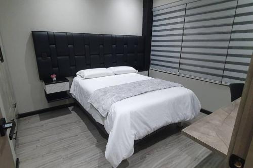 a bedroom with a large bed with a black headboard at Departamento inteligente y acogedor in Cuenca