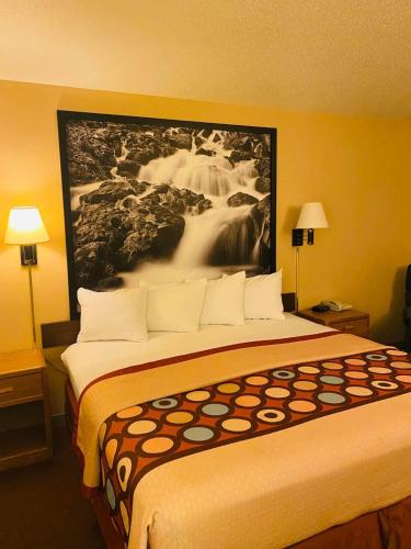a hotel room with a large bed with a painting on the wall at Super 8 by Wyndham Hot Springs in Hot Springs