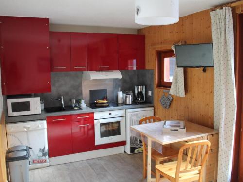 une cuisine avec des placards rouges et une table en bois dans l'établissement Studio cosy à Valloire, 4 pers, proche remontées & centres, balcon, parking - FR-1-263-525, à Valloire