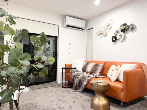 a living room with an orange couch and a table at Christchurch CBD Luxury townhouse in Christchurch