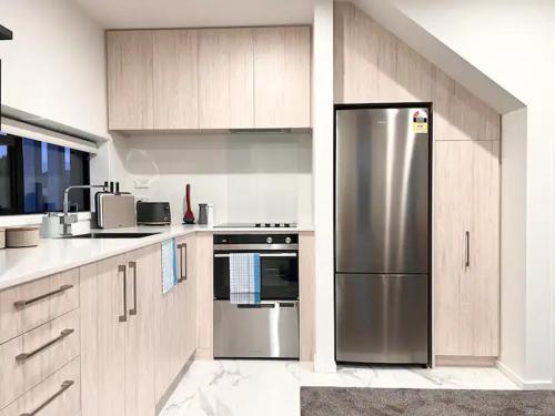 a kitchen with a stainless steel refrigerator and wooden cabinets at Christchurch CBD Luxury townhouse in Christchurch