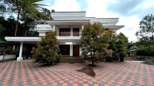 une maison blanche avec des arbres devant elle dans l'établissement Maydale homes, à Kottayam