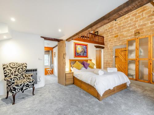 1 dormitorio con 1 cama grande y pared de ladrillo en Manor House Cottage, en Highpeak Junction