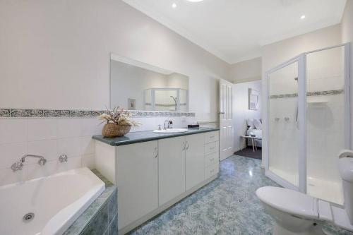 baño blanco con bañera, lavabo y aseo en One bedroom apartment in CBD, en Warrnambool