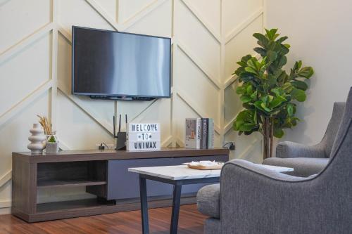 a living room with a tv and two chairs and a table at UNA Sunway Velocity Kuala Lumpur by Unimax in Kuala Lumpur